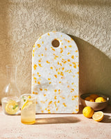 lemon-patterned recycled chopping board with glass pitcher, drink, and fresh lemons