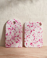 Two dragon fruit-inspired speckled cutting boards with pink and white patterns on a neutral surface