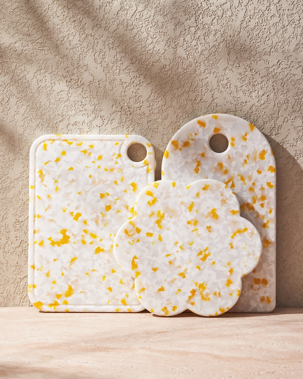 Set of three recycled chopping boards with yellow and white terrazzo pattern on stone surface